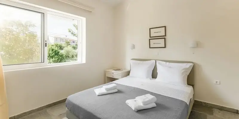 Une chambre lumineuse avec un lit double et une fenêtre.
