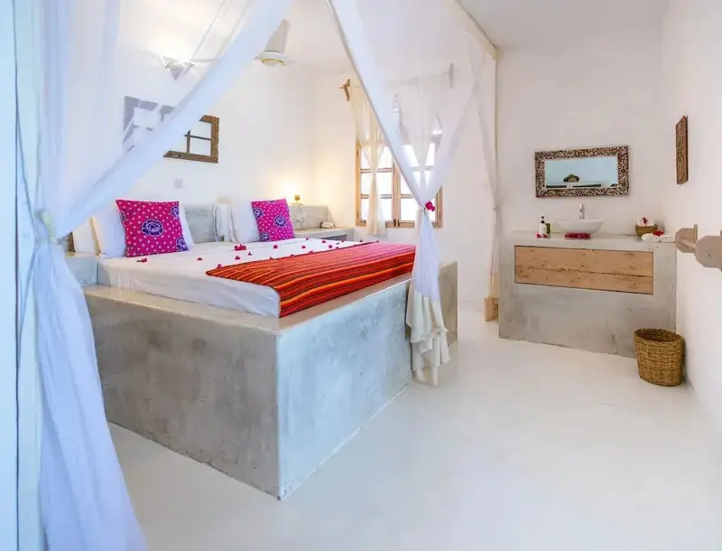 Une chambre lumineuse avec un lit à baldaquin et une salle de bain attenante.