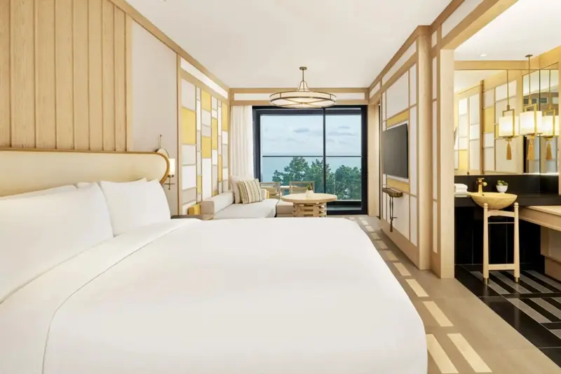 Une chambre lumineuse avec un grand lit et un coin salon près d'une fenêtre.