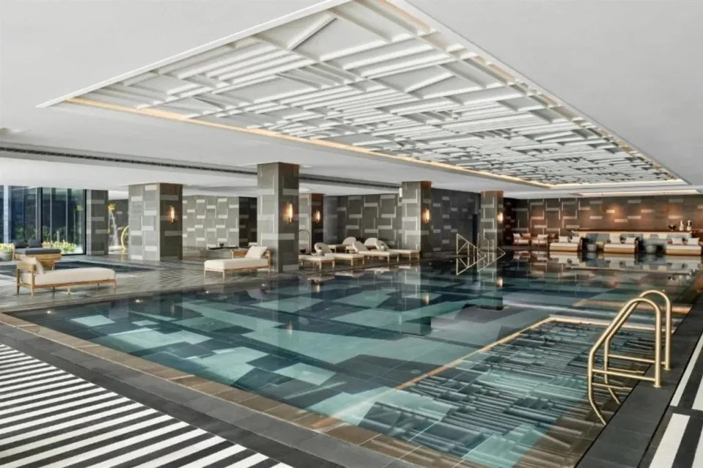 Une piscine intérieure rectangulaire avec des transats et des colonnes décoratives.