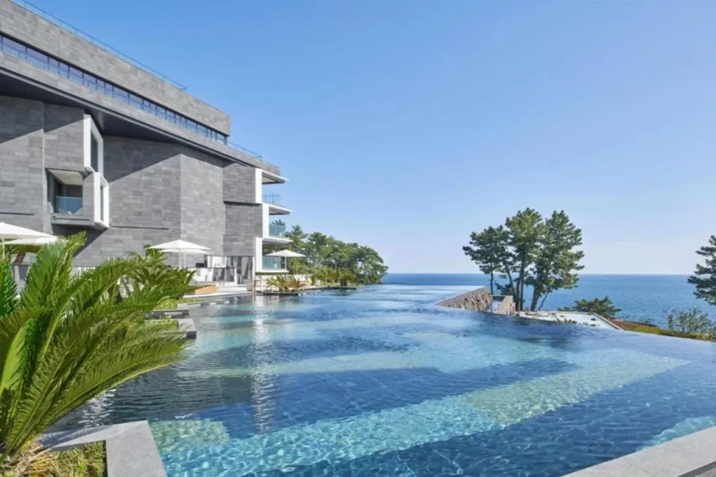 Une piscine à débordement offre une vue sur la mer et les bâtiments environnants.