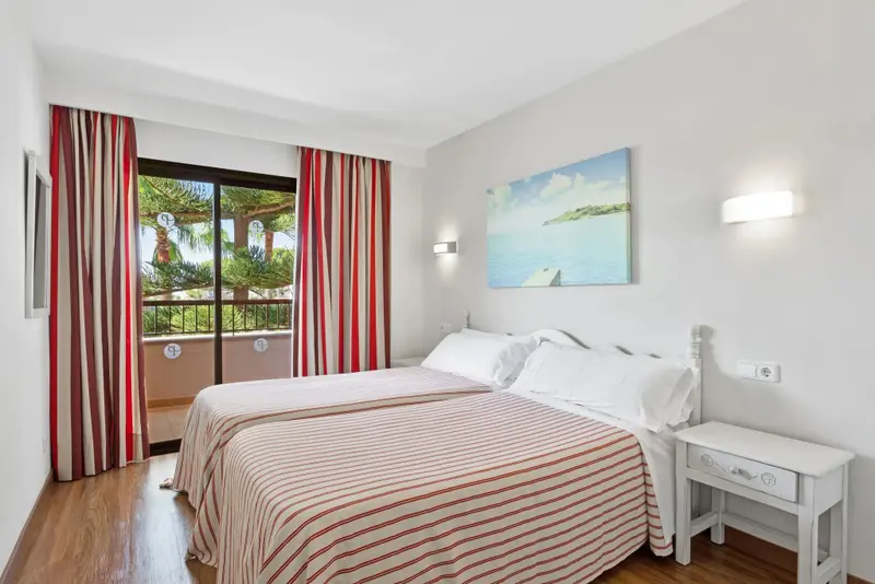 Une chambre lumineuse avec un grand lit et un accès à un balcon.