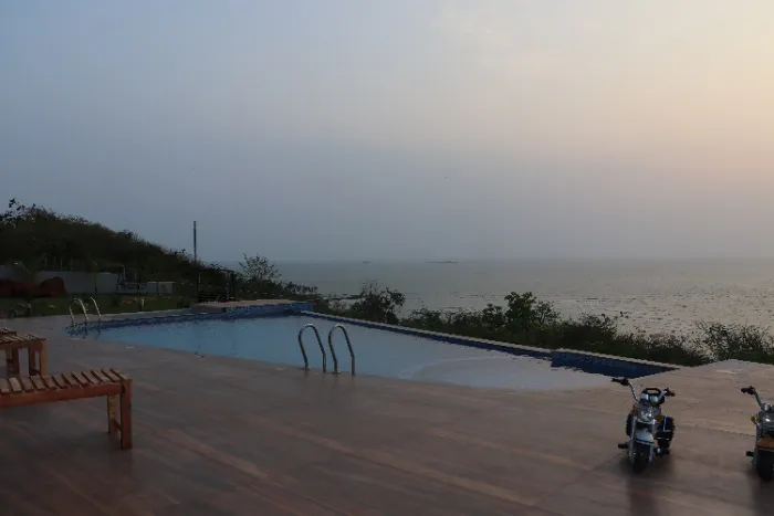 Une piscine rectangulaire avec des marches d'accès, surplombant la mer au loin.
