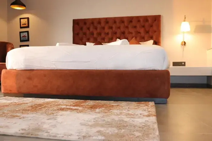 Un grand lit recouvert d'une couette blanche se trouve dans une chambre décorée avec un tapis et des tableaux.