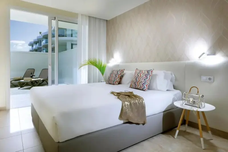 Une chambre lumineuse avec un grand lit et un accès à une terrasse.