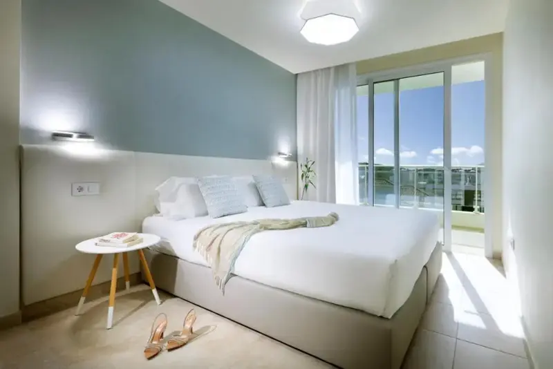 Une chambre lumineuse avec un grand lit et un accès à une terrasse.