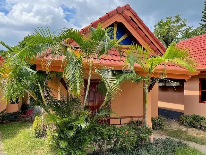 Façade d'un bâtiment aux tons chauds, entouré de végétation tropicale.