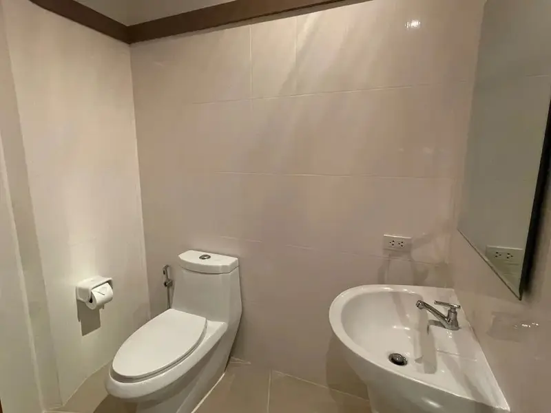 Une salle de bain claire avec des sanitaires blancs et un miroir.
