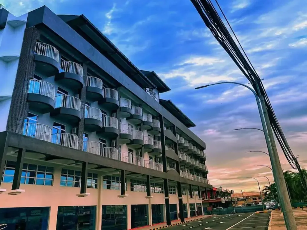 Bâtiment moderne avec de nombreux balcons face à un ciel nuageux.