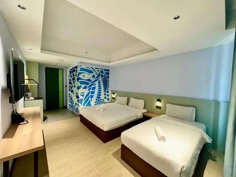 Chambre lumineuse avec deux lits et un mur décoré.