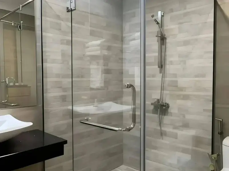 Une douche à l'italienne moderne avec des carreaux gris et des accessoires chromés.