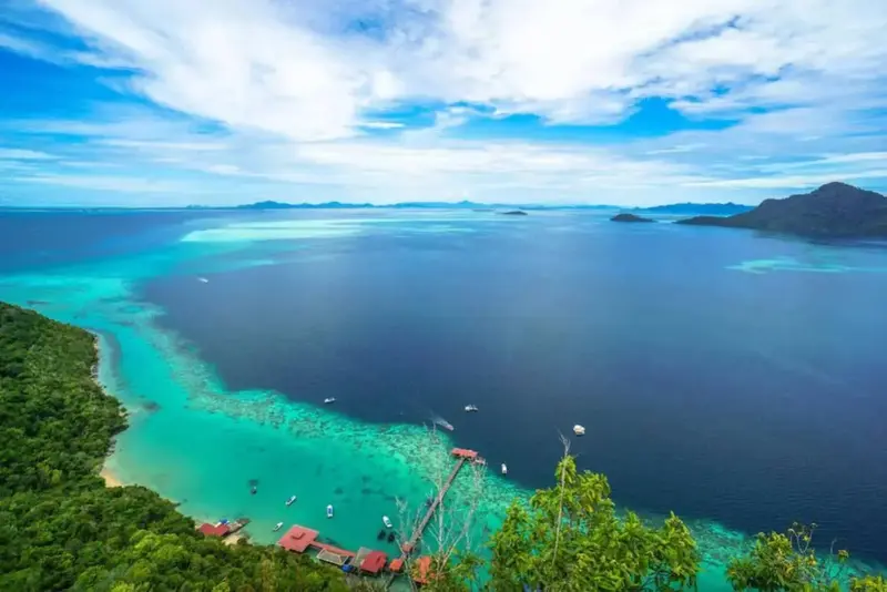 Vue aérienne d'une côte tropicale avec des eaux turquoise et des îles verdoyantes.