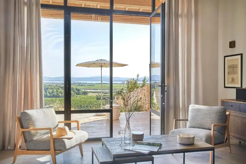 Un espace de détente intérieur offre une vue dégagée sur un paysage verdoyant et la mer.