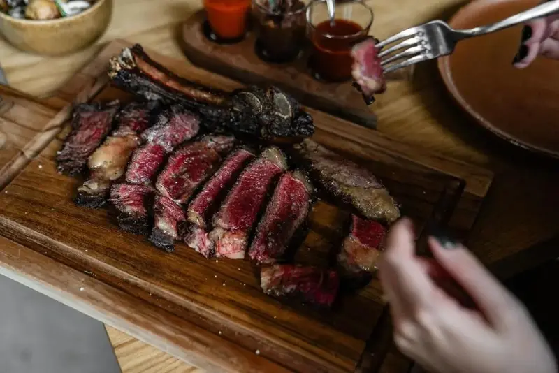 Une portion de viande grillée est présentée sur une planche en bois, prête à être dégustée.