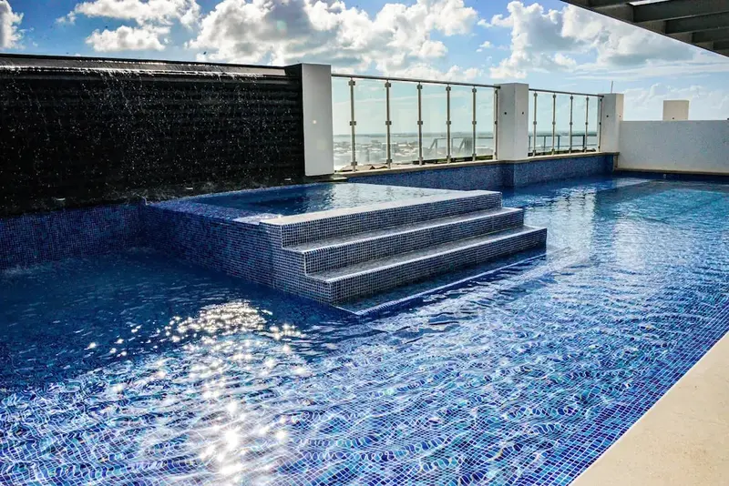 Une piscine rectangulaire avec des marches et une cascade artificielle.