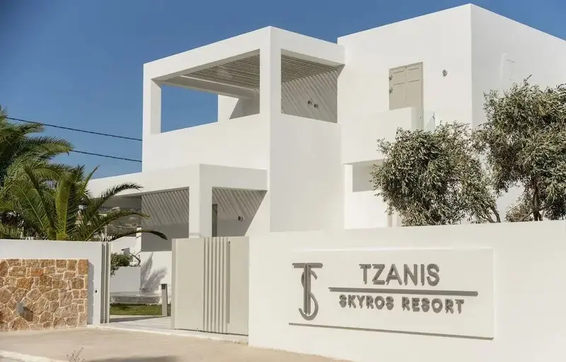 Façade blanche d'un bâtiment moderne avec une entrée et une végétation soignée.