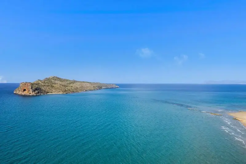 Vue aérienne d'une côte rocheuse et d'une plage de sable fin baignée par une mer turquoise.