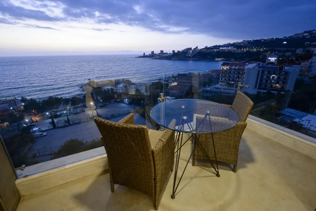 Terrasse avec table et chaises donnant sur la mer au crépuscule.