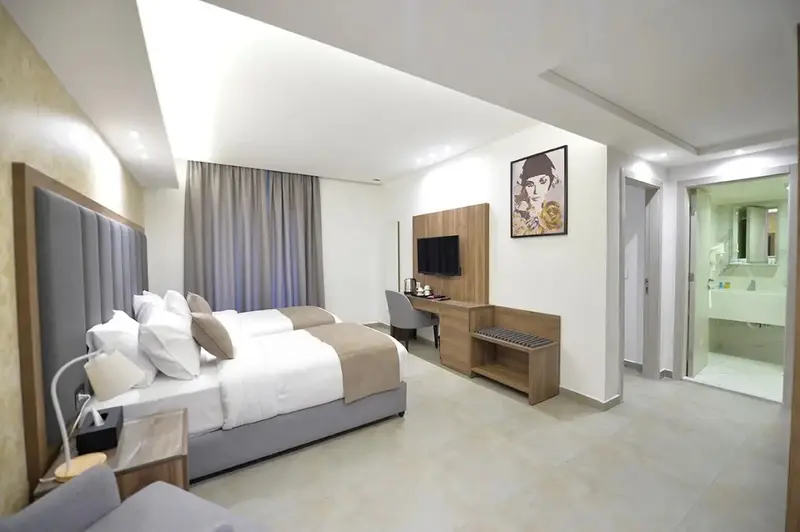 Une chambre lumineuse avec deux lits simples et une salle de bain attenante.