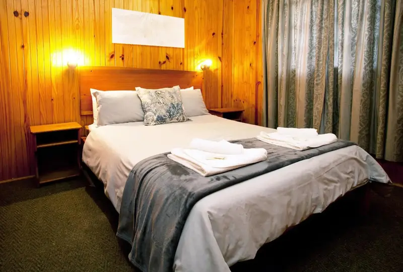 Une chambre lumineuse avec un grand lit recouvert d'une couverture et de coussins.