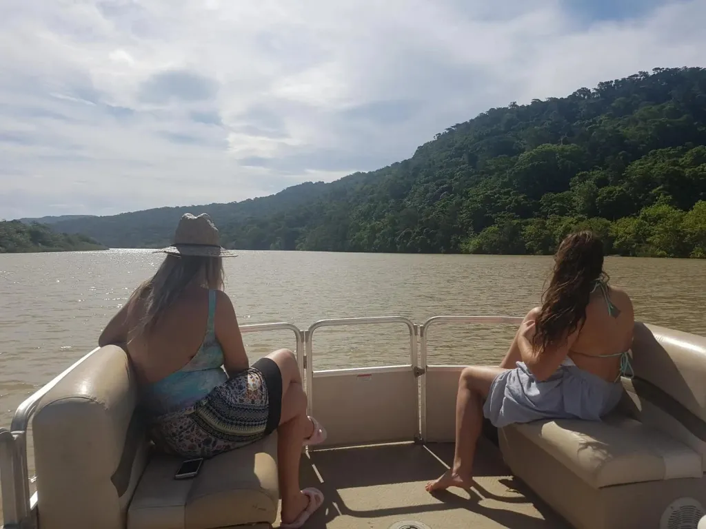 Deux personnes sont assises face à un paysage montagneux depuis un bateau.