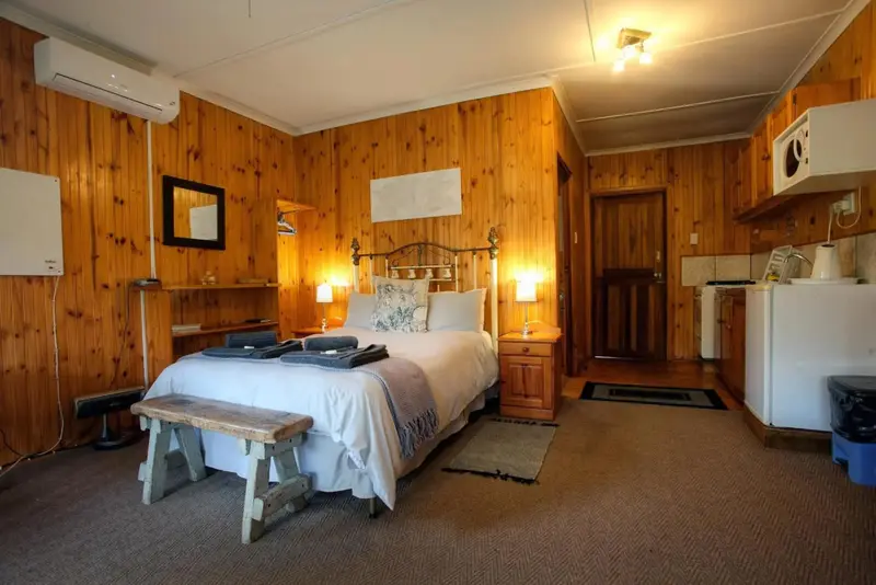 Une chambre lumineuse avec un lit fait et un coin cuisine.