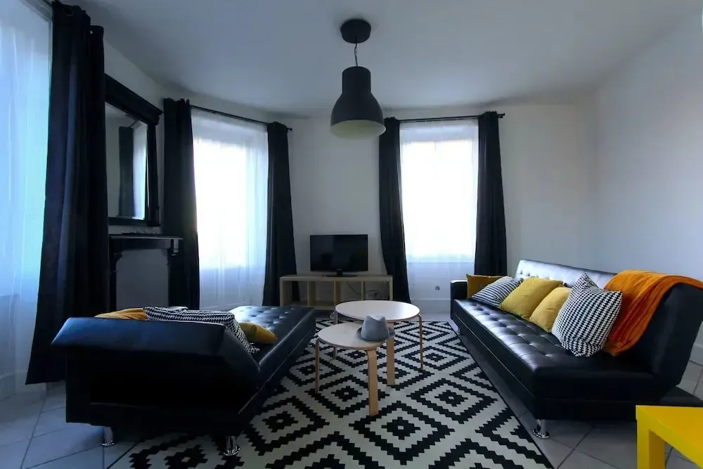Un salon moderne avec un canapé d'angle noir et des coussins colorés.