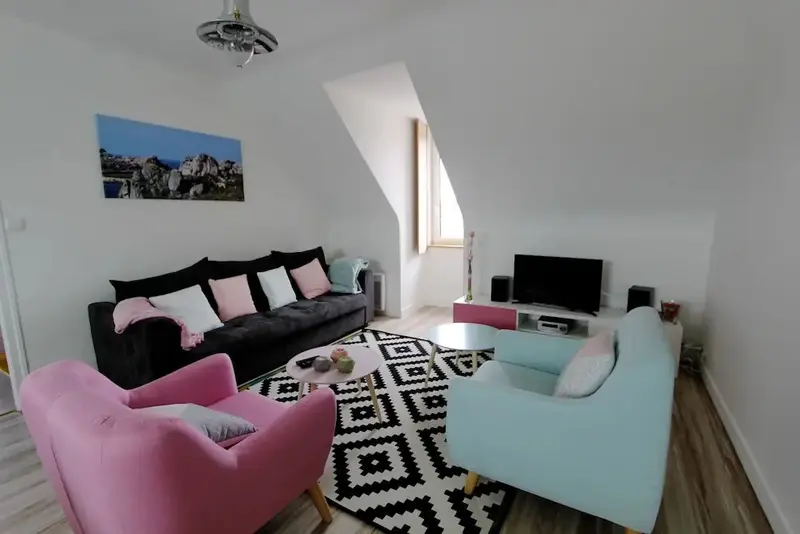 Espace de vie lumineux avec canapés et fauteuils colorés.