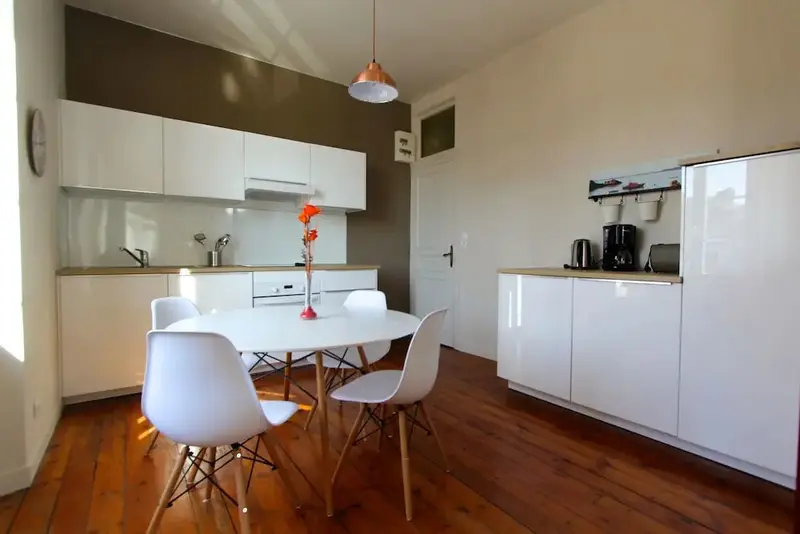 Une cuisine lumineuse avec une table à manger et des chaises.