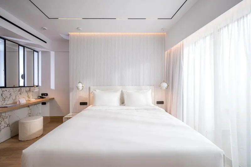 Une chambre lumineuse avec un grand lit et un bureau.