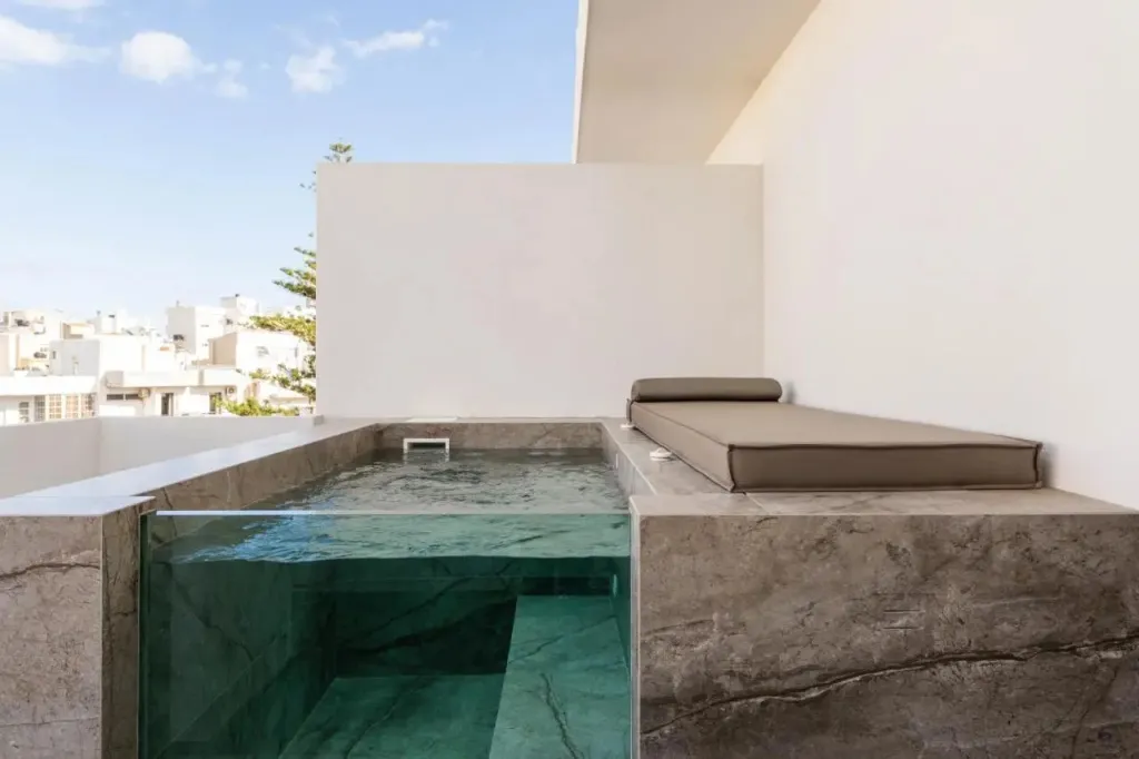 Une terrasse avec une petite piscine à débordement et un espace de repos.
