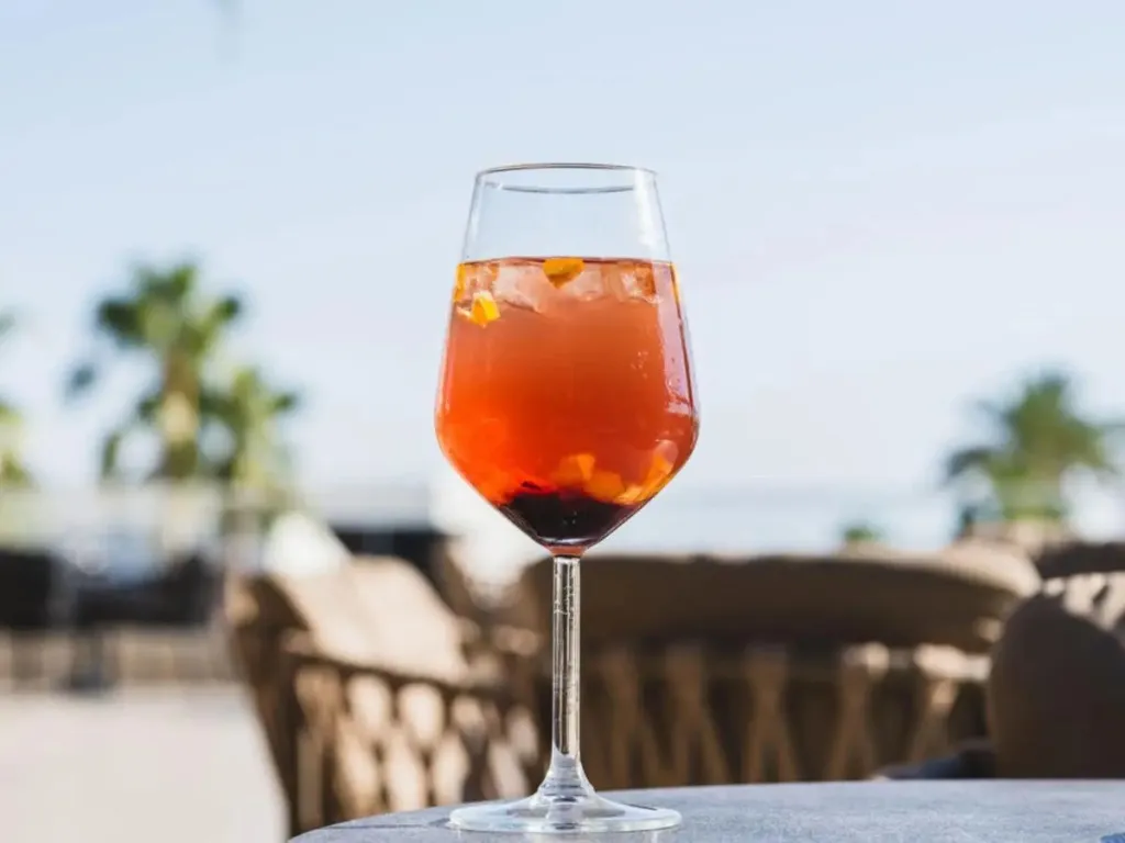 Un verre de cocktail rafraîchissant est posé sur une table en extérieur.