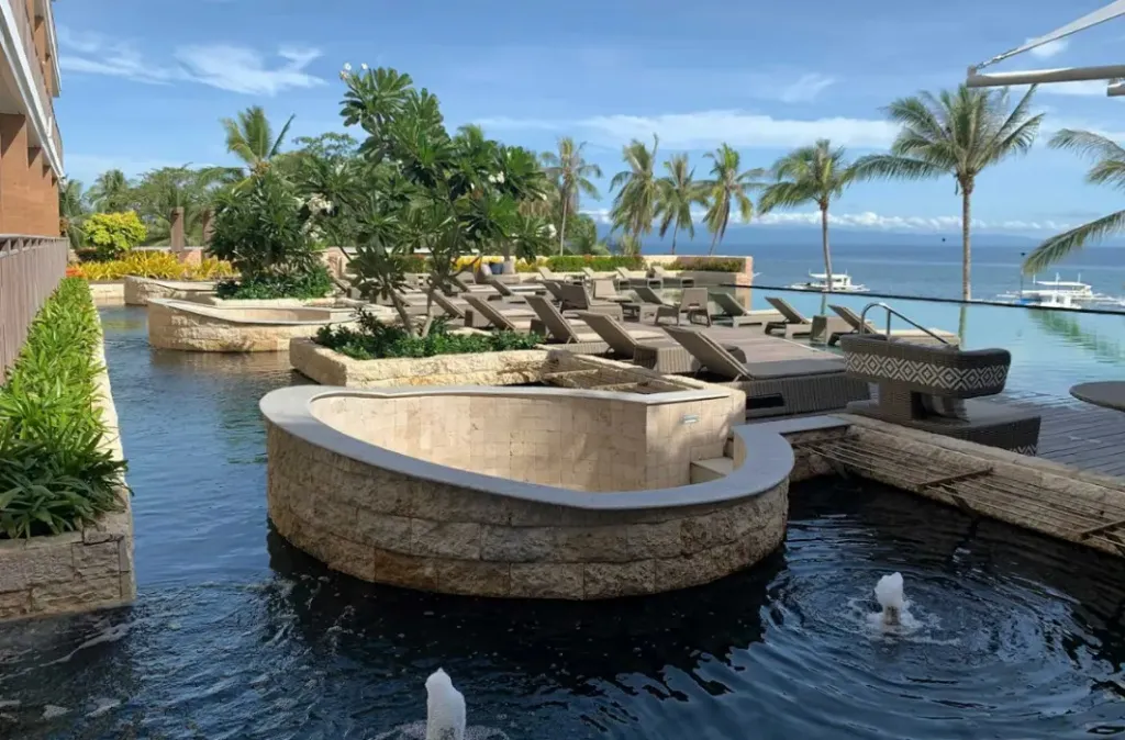 Transats alignés au bord d'une piscine à débordement avec vue sur la mer.