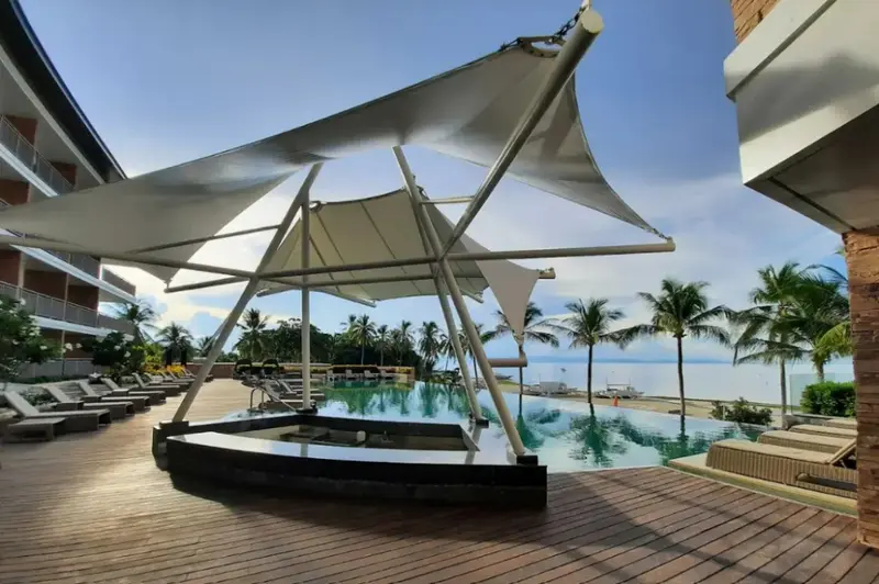 Terrasse ombragée avec piscine et vue sur la mer.