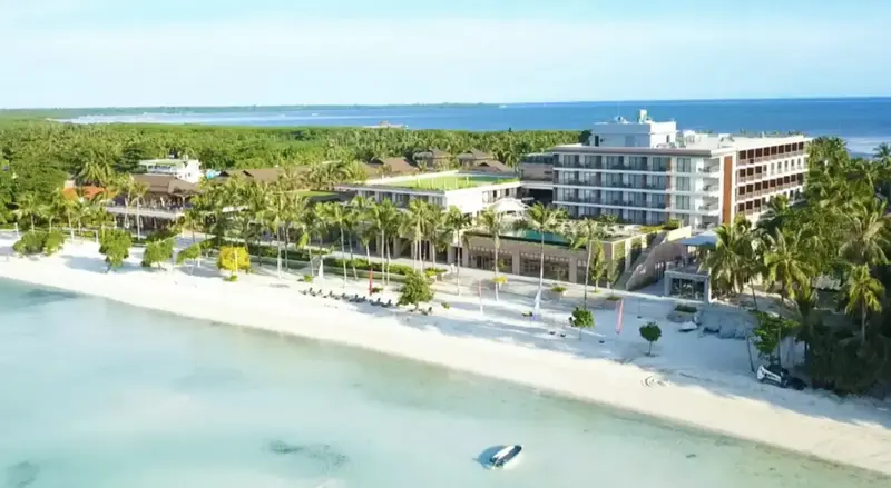 Vue aérienne d'un complexe hôtelier bordant une plage de sable blanc et une mer turquoise.
