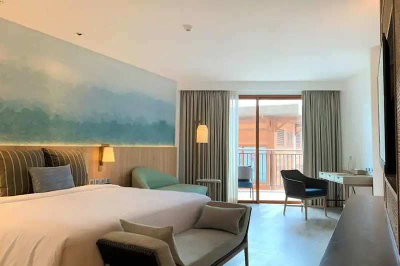 Une chambre lumineuse avec un grand lit et un accès à un balcon.