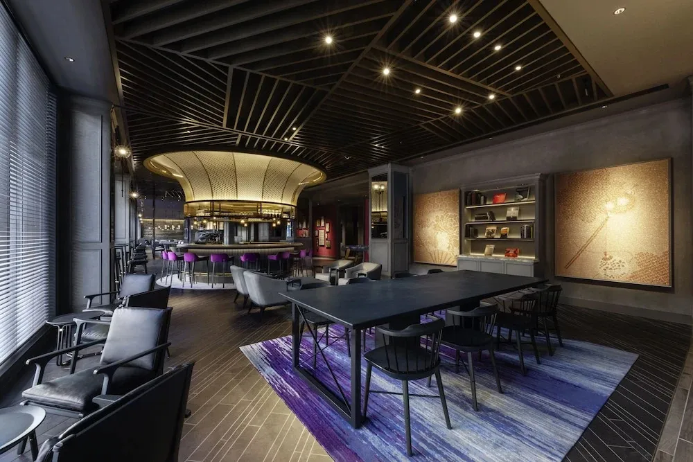 Un espace de détente intérieur avec des tables, des chaises et un bar en arrière-plan.