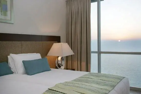 Une chambre lumineuse avec un lit et une vue sur la mer au coucher du soleil.