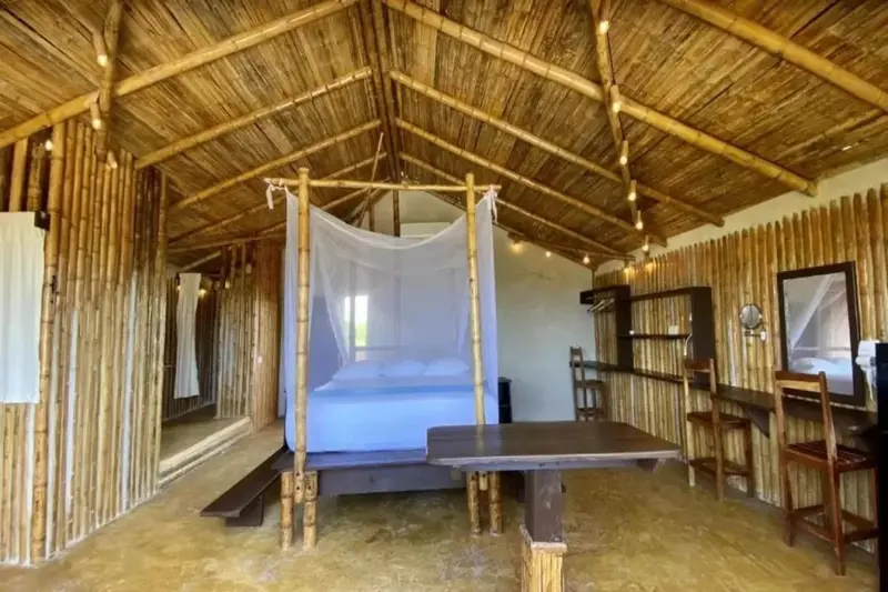 Une chambre rustique avec un lit à baldaquin et un coin repas en bois.