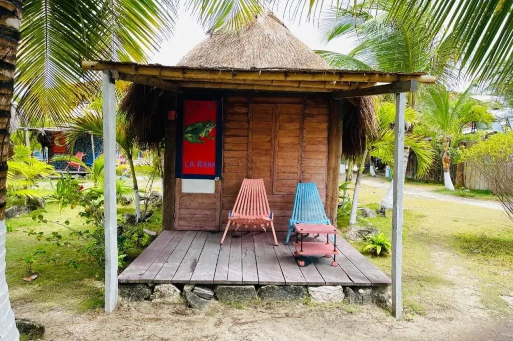 Une petite cabane en bois avec une terrasse et deux chaises colorées.