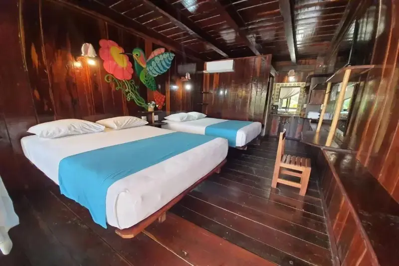 Une chambre avec deux lits recouverts de draps blancs et bleus, décorée de peintures murales colorées.