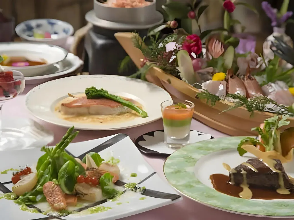 Une table est dressée avec plusieurs plats raffinés et décorée de fleurs.
