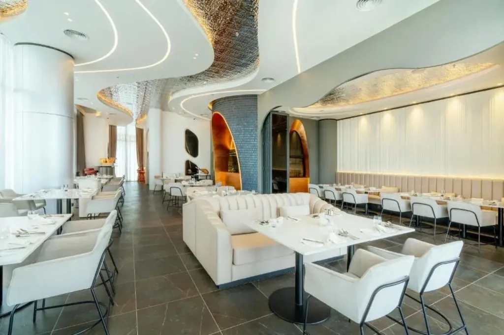 Une salle lumineuse avec des tables dressées et des banquettes confortables.