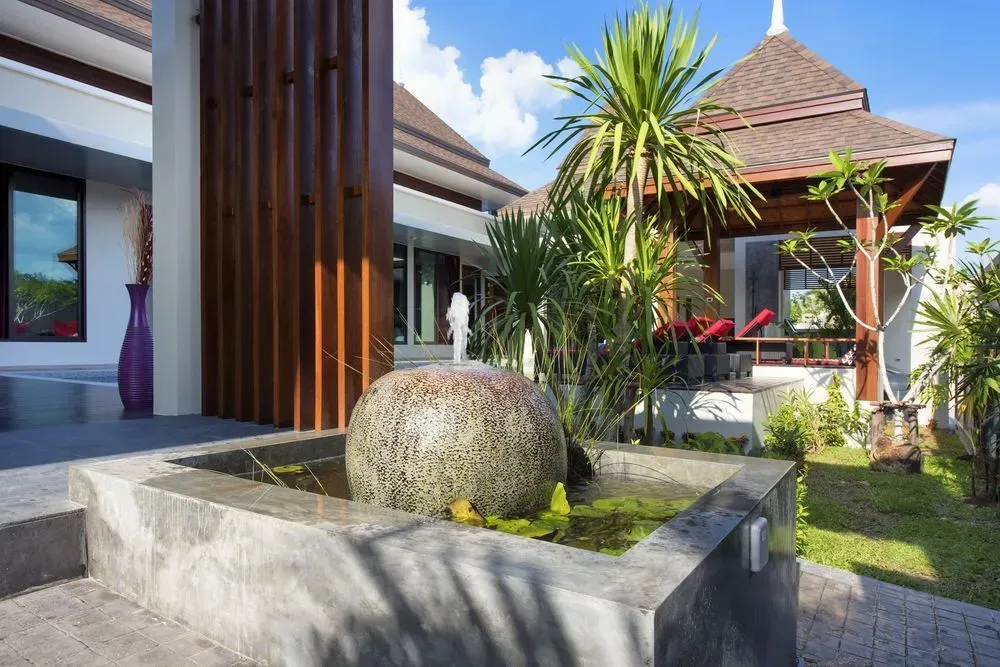 Une fontaine orne un espace extérieur soigné avec une végétation luxuriante.