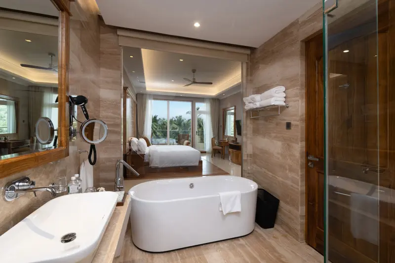 Une salle de bain spacieuse avec baignoire et douche donnant sur une chambre lumineuse.