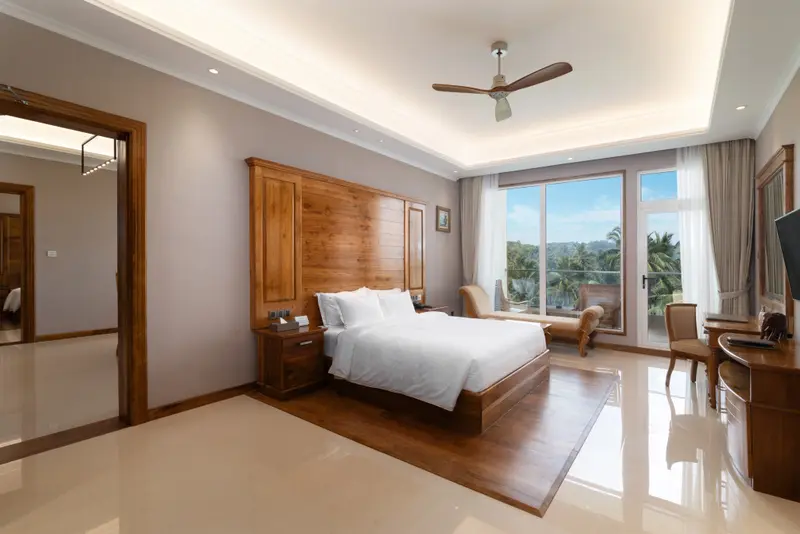 Une chambre lumineuse avec un grand lit et une vue sur la végétation.