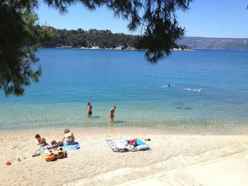 Une plage de sable avec des personnes se baignant et se relaxant au soleil.