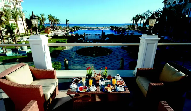 Une table basse est dressée avec un petit-déjeuner sur une terrasse ensoleillée.
