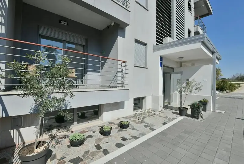 Façade moderne d'un bâtiment avec des balcons et des plantations.