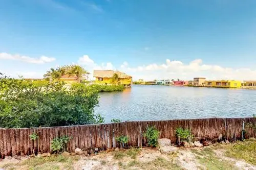 Vue d'ensemble d'habitations colorées au bord de l'eau sous un ciel nuageux.